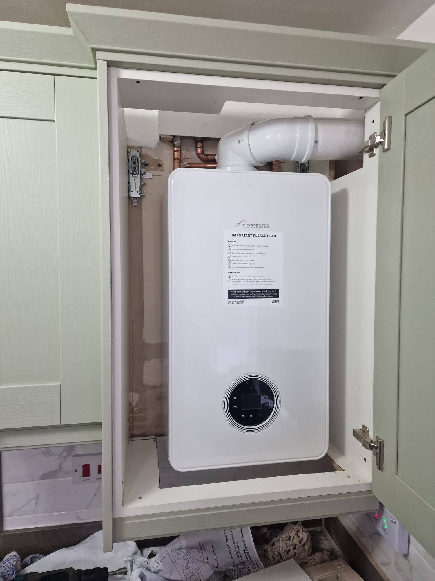 Worcester Bosch combi boiler neatly installed in a green shaker kitchen cabinet