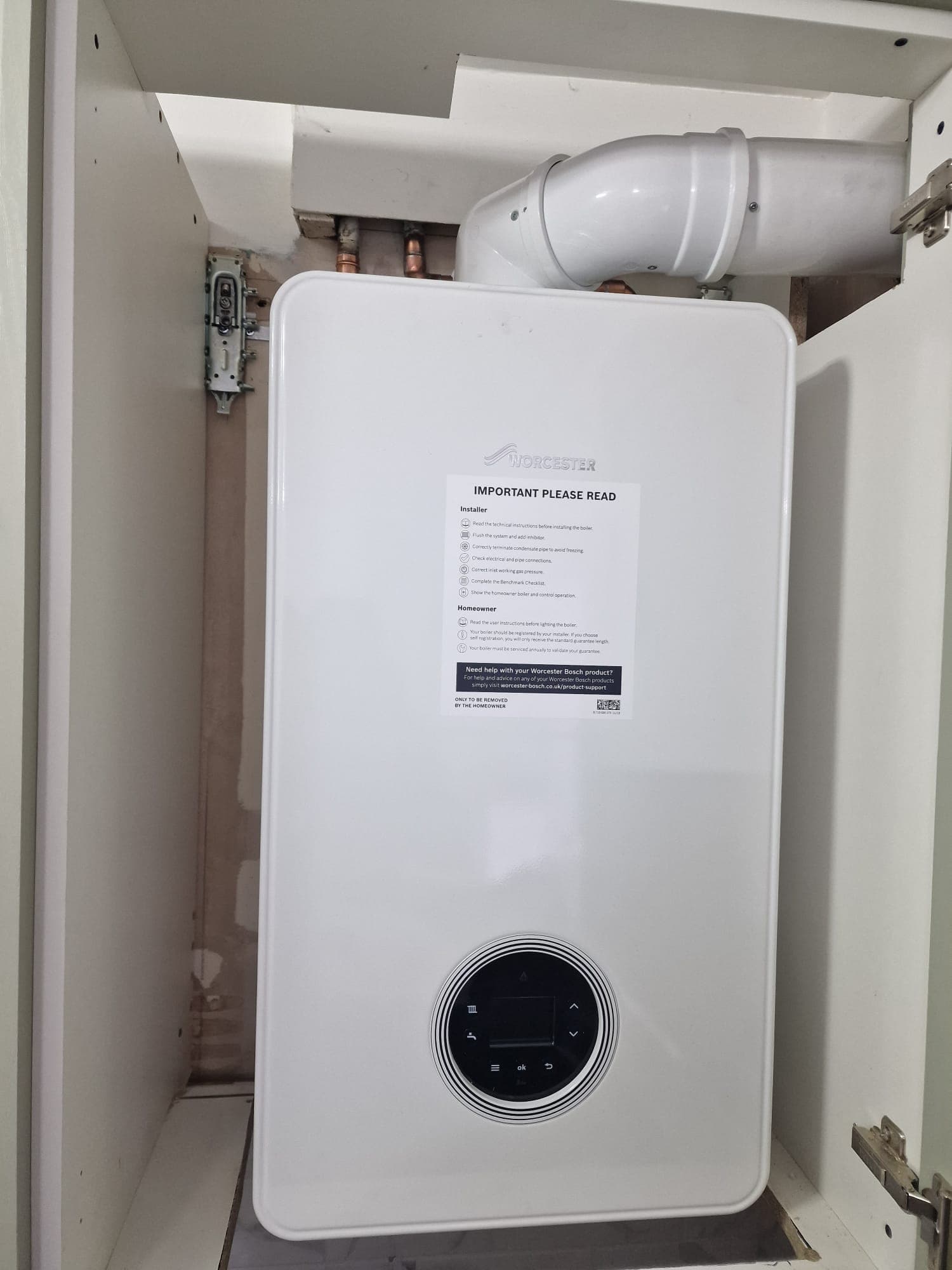 Worcester Bosch combi boiler installed in a tall kitchen cabinet — clean finished installation